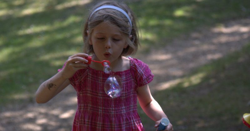 Une petite fille qui souffle des bulles de savon